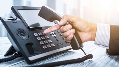 A hand about to touch a button on a business telephone